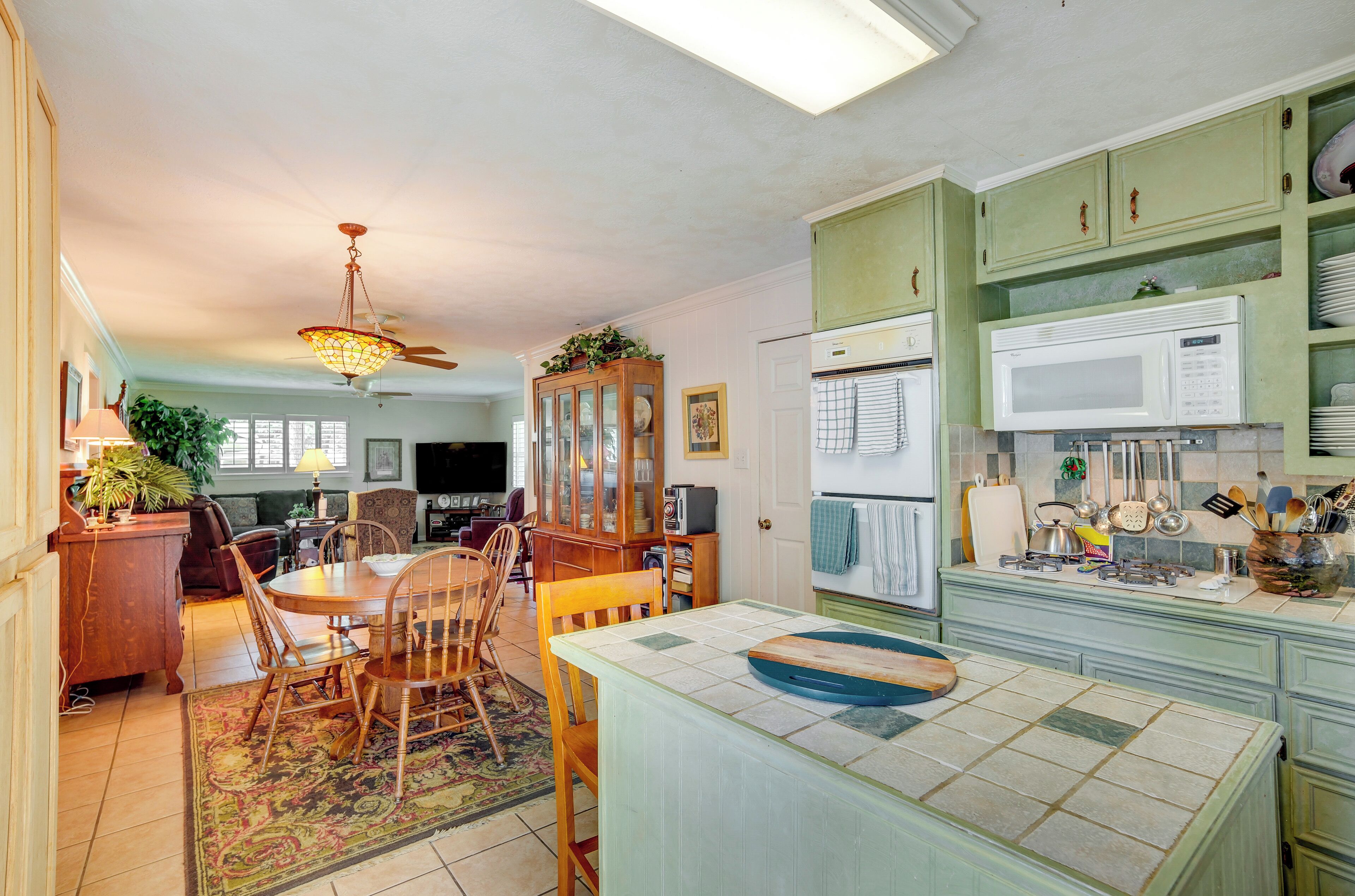 A kitchen with a dining table, chairs, a microwave, and cabinets.