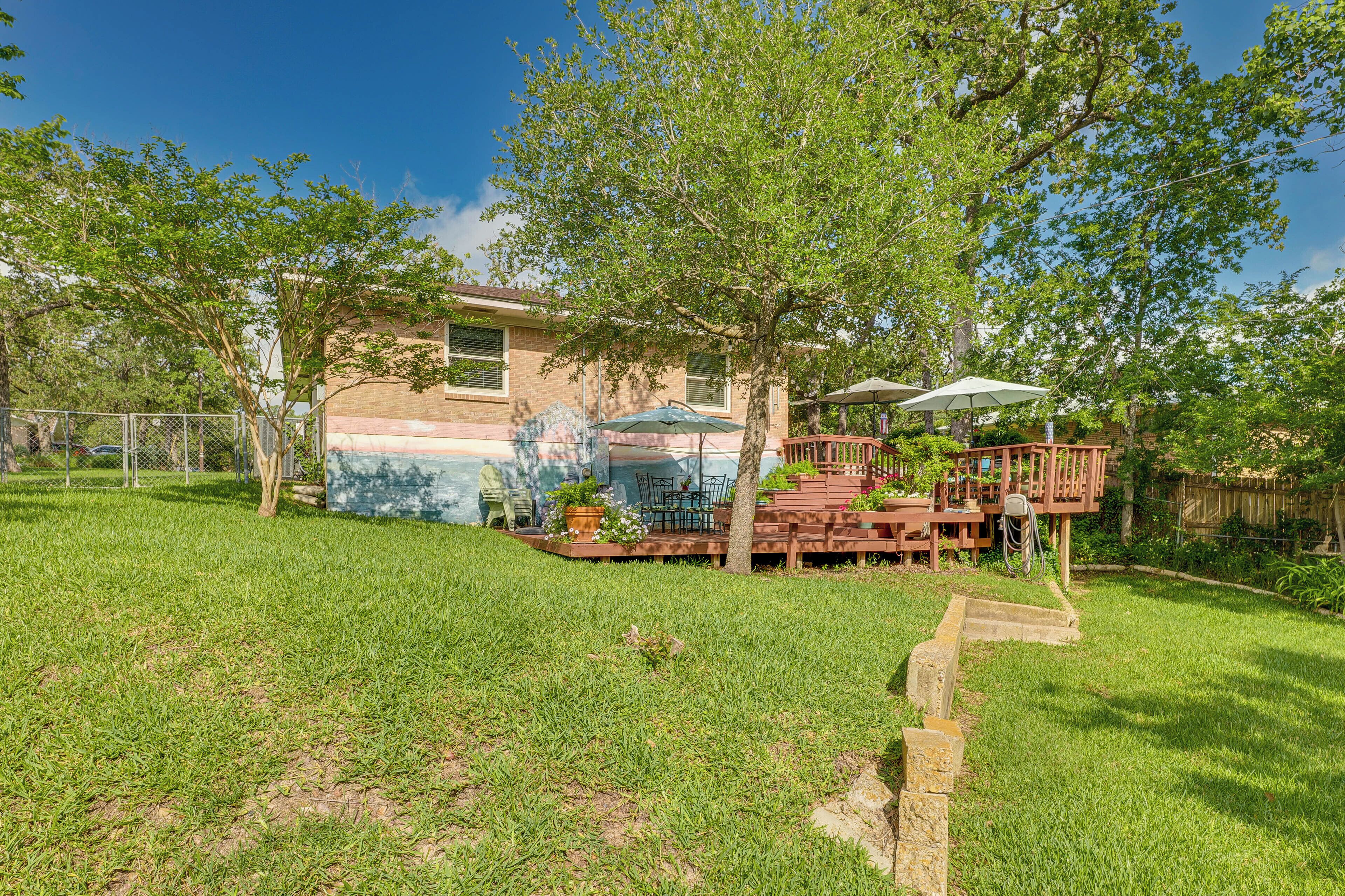 A backyard with a wooden deck, a patio table, and a covered seating area.