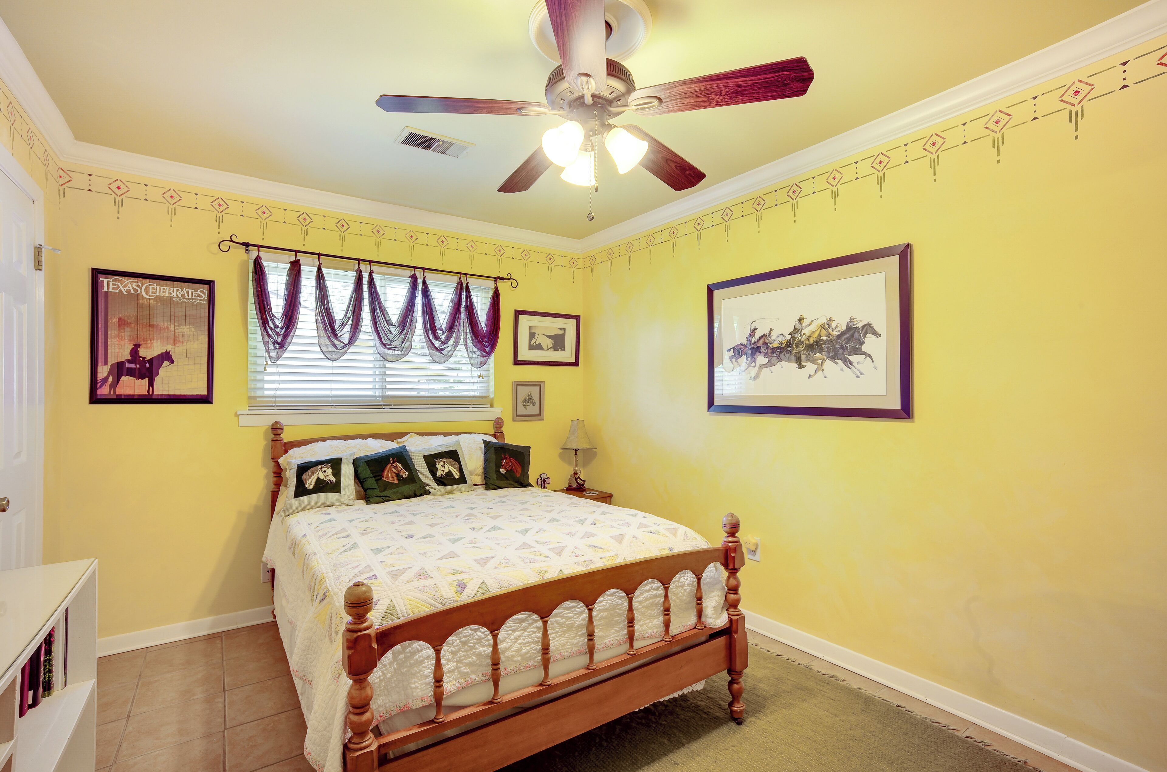 Une chambre à coucher avec un lit en bois, un ventilateur de plafond et des murs jaunes.