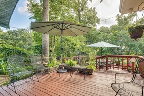 A wooden deck with metal chairs and a table, surrounded by lush greenery and trees. - Lovely Bryan Home w/ Deck - 4 Mi to Kyle Field! (Bryan)