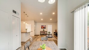 Une cuisine moderne avec des meubles blancs, un coin repas doté d’une table ronde et un salon avec un canapé et une table basse.