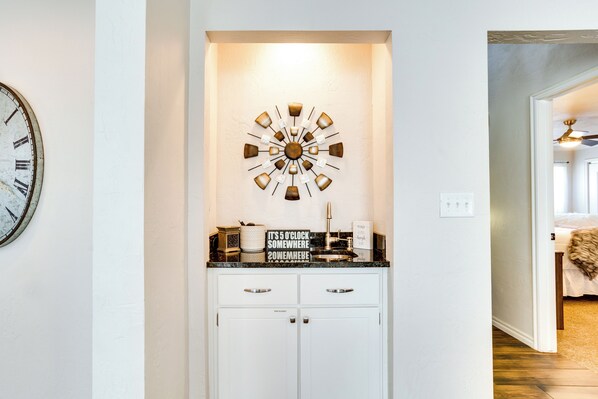 Una cocina con armarios blancos, encimera negra y un reloj decorativo.