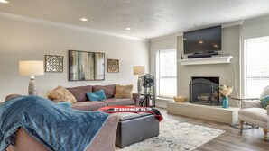A living room with a fireplace, a sofa, a coffee table, and a television mounted above the fireplace. - < 1 Mi to OU Campus - Norman Vacation Rental (Norman)