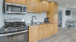 A kitchen with wooden cabinets, a stainless steel stove, a microwave, and a coffee maker. - Sunny Seaside Heights Retreat: Walkable Location! (Seaside Heights)