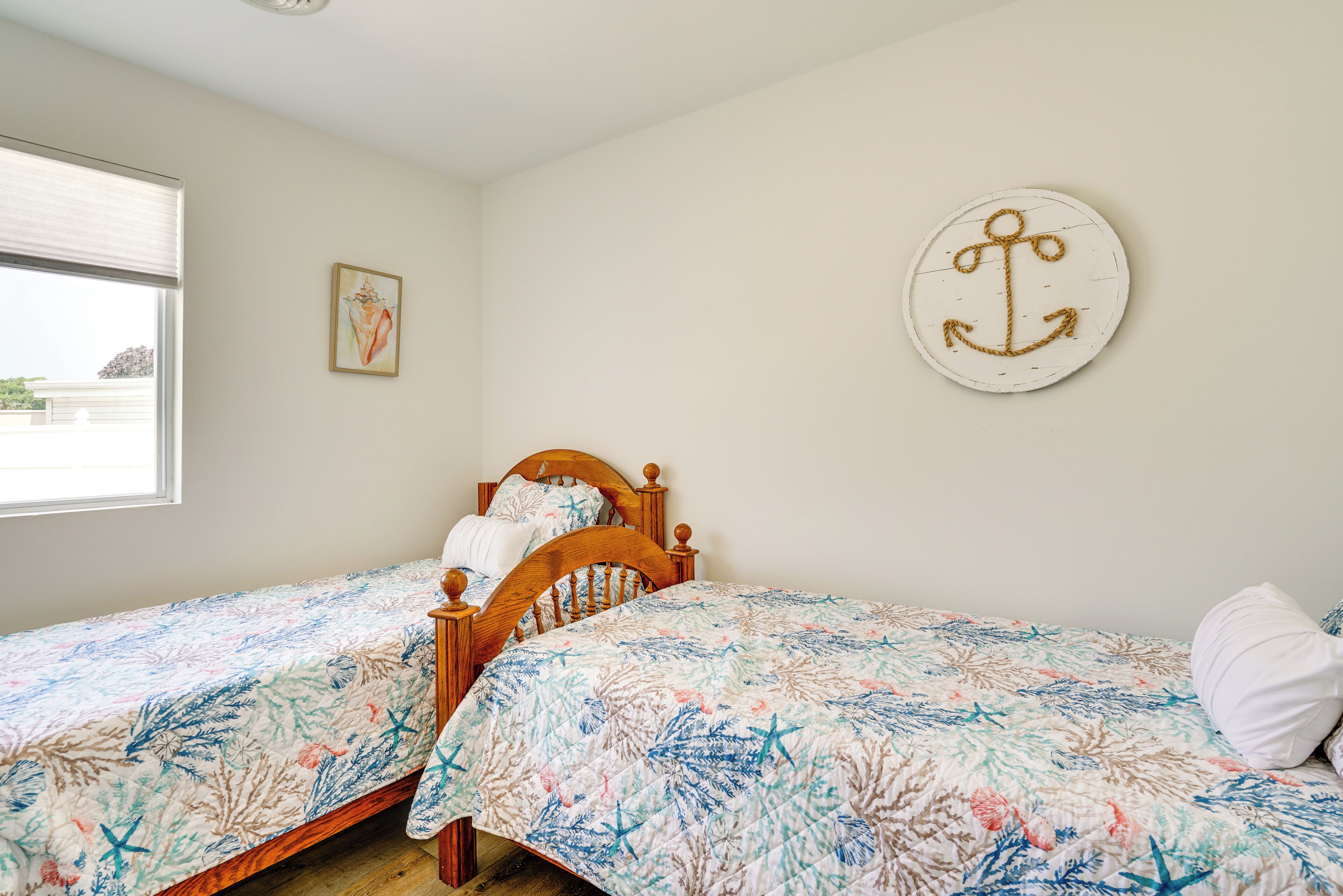 Ein Schlafzimmer mit zwei Holzbetten, jeweils mit einem blumendrucken Bettbezug.