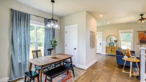A spacious living area with a wooden dining table, benches, a blue sofa, and a small wooden side table. - Getaway w/ Fire Pit: 3 Mi to River Arts District! (Asheville)
