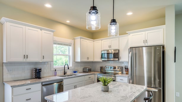 A modern kitchen with white cabinets, stainless steel appliances, a granite countertop, and pendant lighting. - Getaway w/ Fire Pit: 3 Mi to River Arts District! (Asheville)