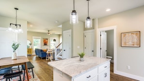 A modern kitchen with a granite countertop, white cabinetry, and pendant lighting. - Getaway w/ Fire Pit: 3 Mi to River Arts District! (Asheville)