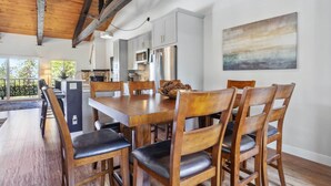 A modern kitchen with white cabinets, stainless steel appliances, and a wooden dining table with chairs. - 10 Mi to Palisades Tahoe! Condo w/ Game Room (Tahoe City)