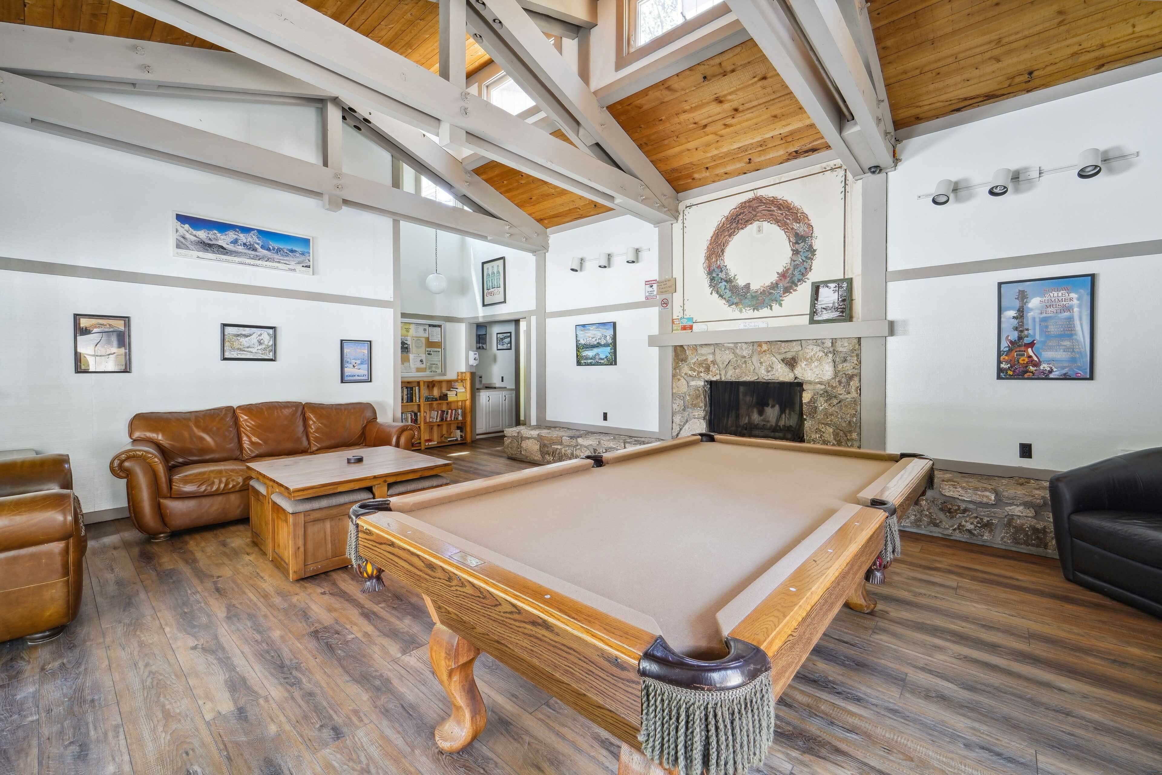 A spacious living room with a pool table, leather sofas, and a fireplace.