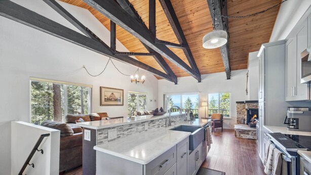 A spacious kitchen with a large island, wooden beams on the ceiling, and a stone fireplace. - 10 Mi to Palisades Tahoe! Condo w/ Game Room (Tahoe City)