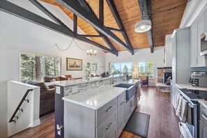 A spacious kitchen with a large island, wooden beams on the ceiling, and a stone fireplace. - 10 Mi to Palisades Tahoe! Condo w/ Game Room (Tahoe City)