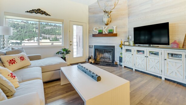 A modern living room with a fireplace, a mounted deer head, a television, and a white sofa. - Brian Head Rental w/ Community Hot Tub & Sauna! (Brian Head)