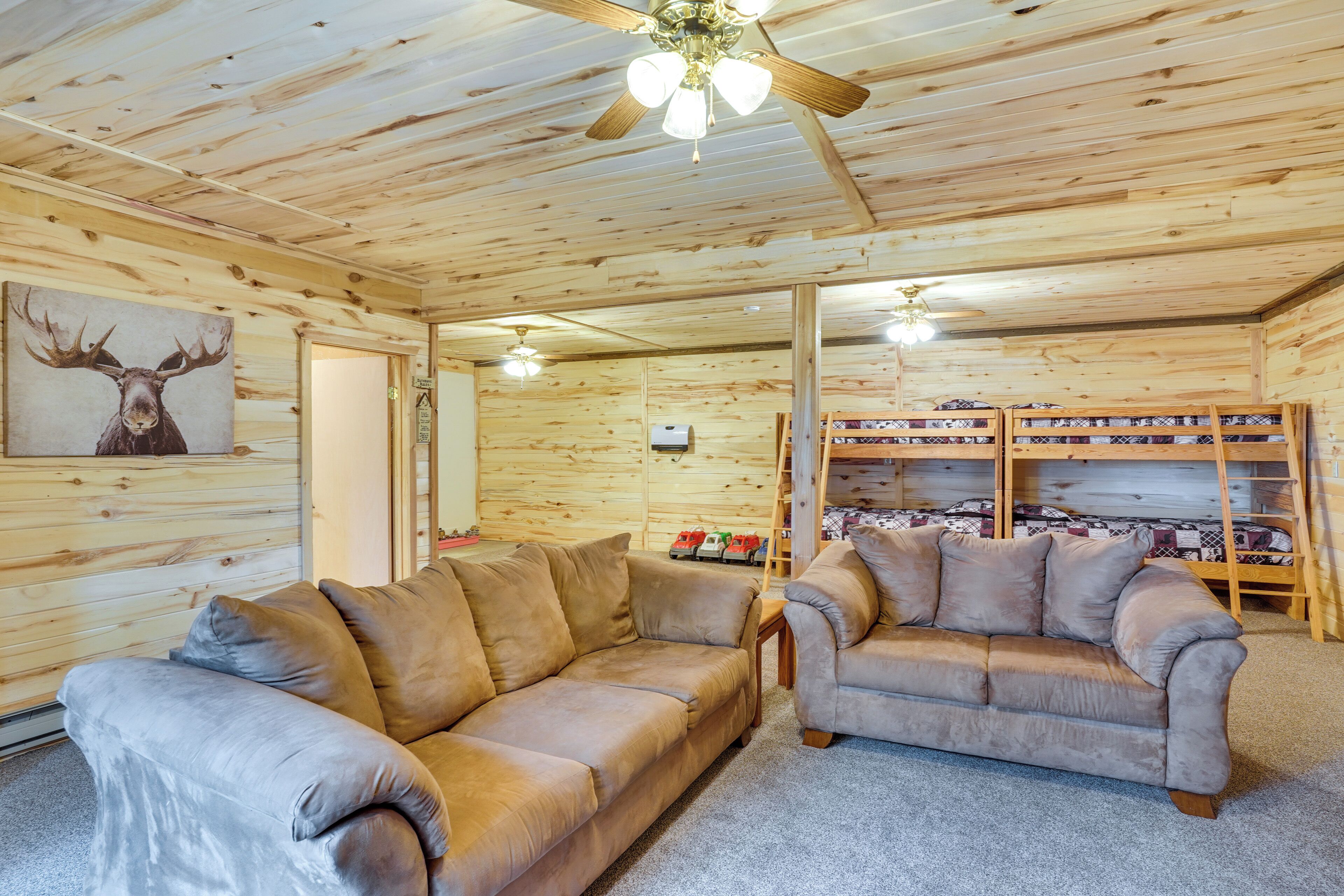 A log cabin interior with two sofas, a ceiling fan, and a shoe rack.