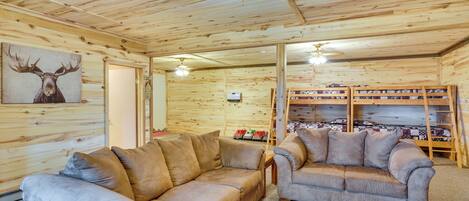 A log cabin interior with two sofas, a ceiling fan, and a shoe rack.