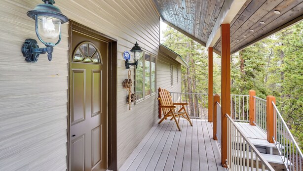 A wooden deck with a railing, a door, and two wall-mounted lanterns. - Spacious Beaver Getaway Near Eagle Point Resort! (Beaver)