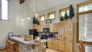 A kitchen with a stone island, wooden cabinets, and a bar area with stools. - Spacious Beaver Getaway Near Eagle Point Resort! (Beaver)