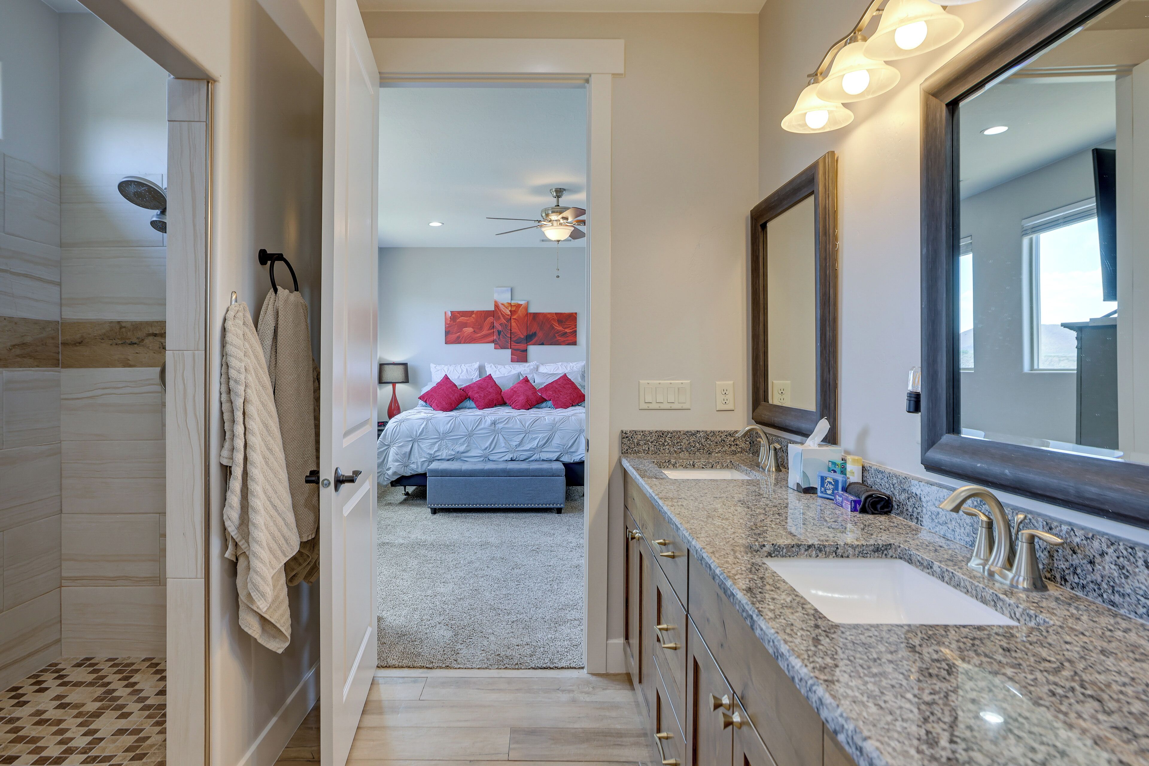 Un baño moderno con un espejo grande, encimera de granito y cabina de ducha a ras de suelo.