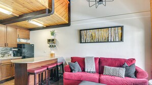 Eine moderne Küche mit Holzschränken, einem schwarzen Kühlschrank und einer Bar mit Hockern.