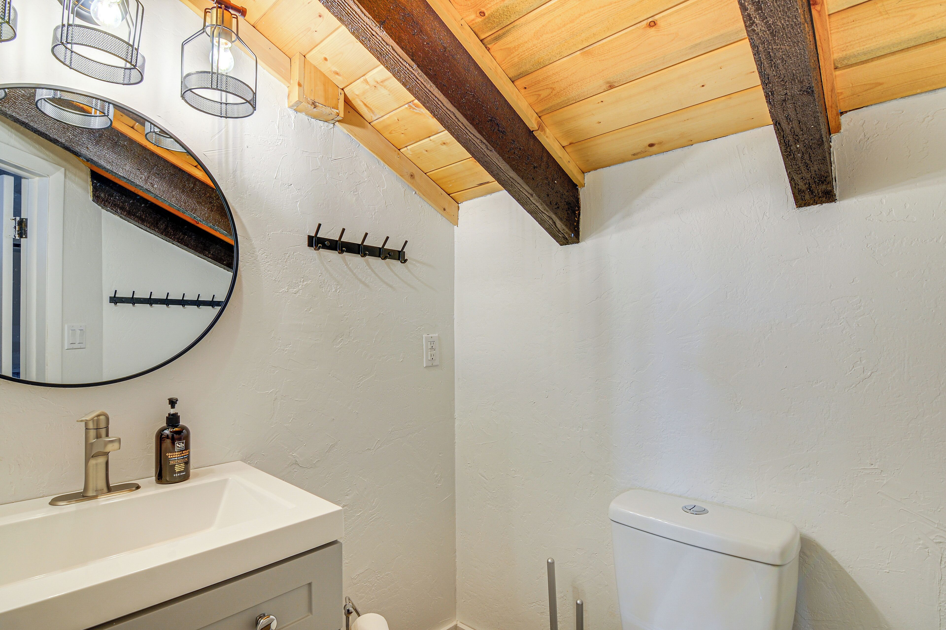 A bathroom with a white sink, a mirror, and a toilet.