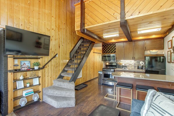 A wooden interior with a staircase, kitchen, and living area.