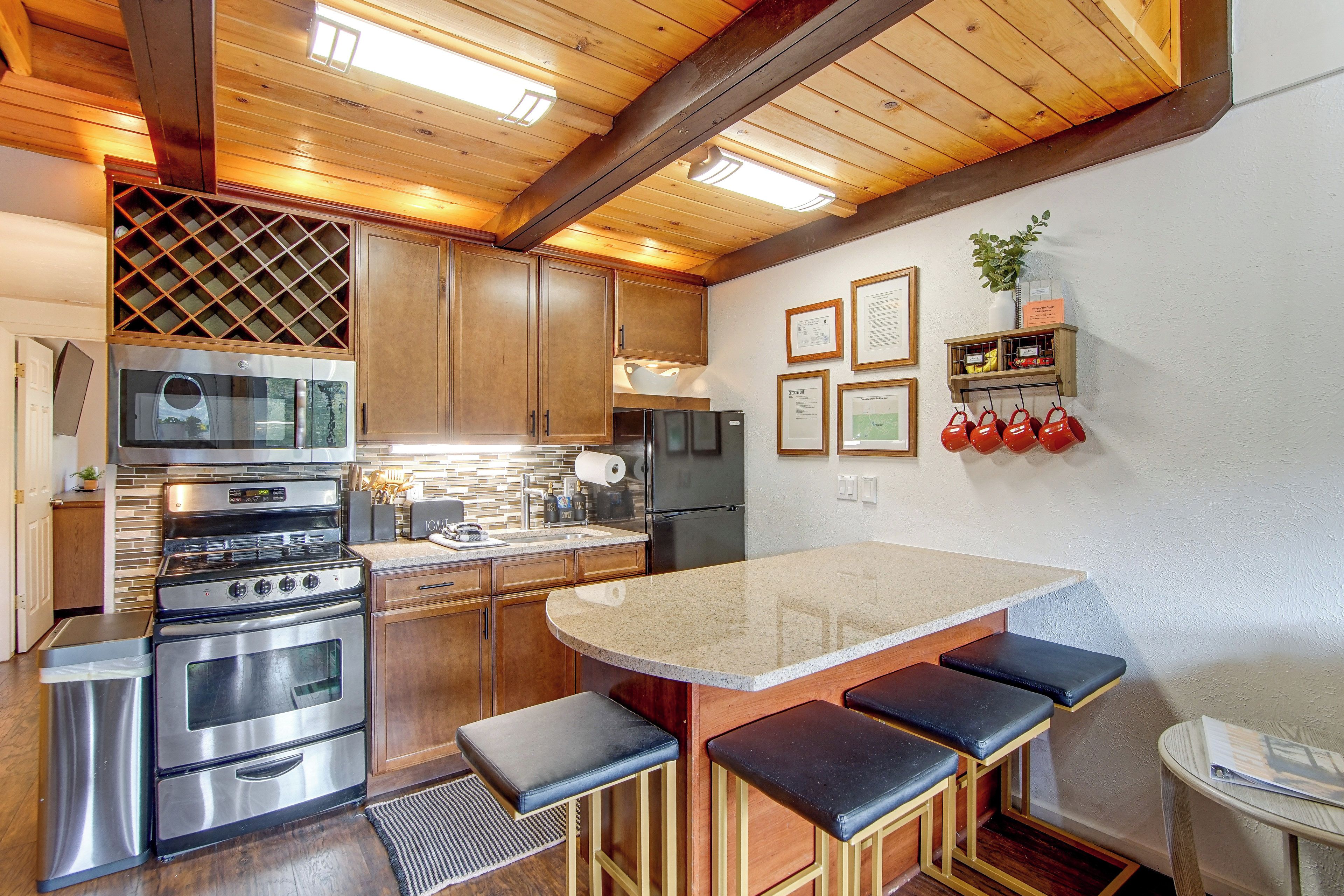 Una cocina moderna con electrodomésticos de acero inoxidable, armarios de madera y una zona de bar con taburetes.