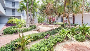 A courtyard with palm trees, various plants, and a brick pathway. - Ocean-view Key Colony Beach Condo w/ Pool Access! (Key Colony Beach)