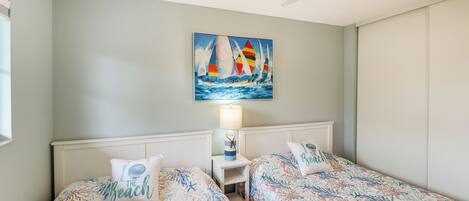 Ein Schlafzimmer mit zwei Betten, einem Deckenventilator und einem Bild von Segelbooten an der Wand.