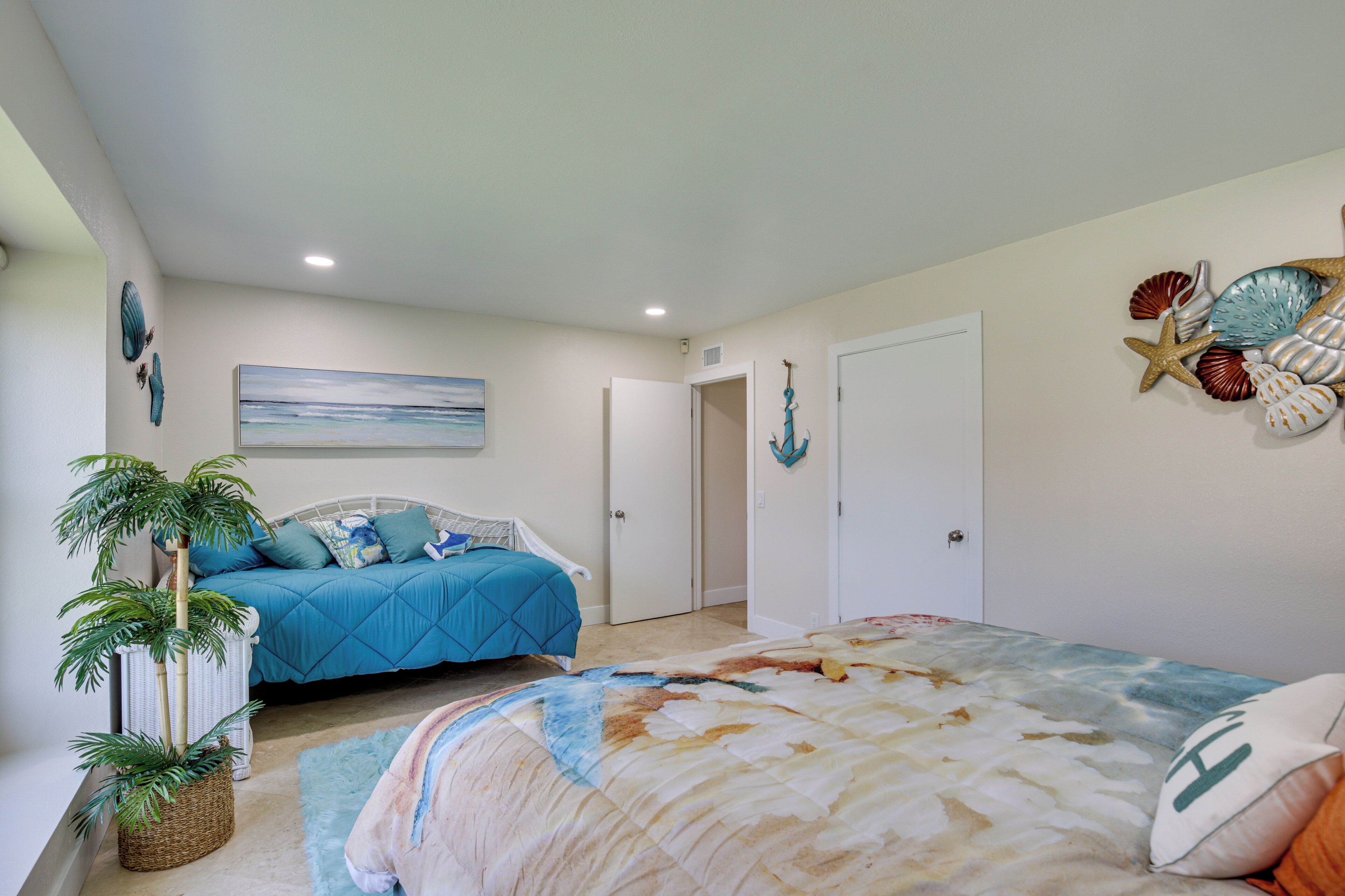 A bedroom with a bed, a potted plant, and a wall with decorative shells.