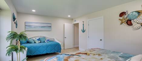 A bedroom with a bed, a potted plant, and a wall with decorative shells.