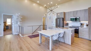Una cocina moderna con una isla central, electrodomésticos de acero inoxidable y una lámpara de diseño contemporáneo.