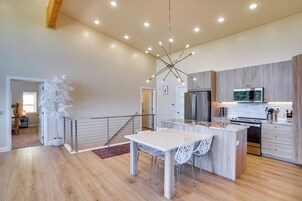 A modern kitchen with a central island, stainless steel appliances, and a contemporary light fixture.