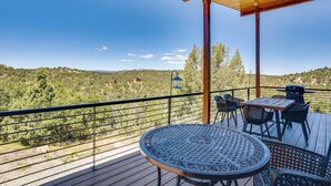 Una terraza de madera con una mesa y sillas, con vistas a un paisaje montañoso.