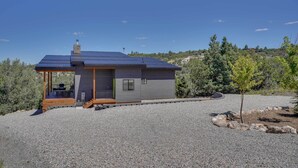 Una casa moderna con porche cubierto, chimenea y camino de entrada de grava.