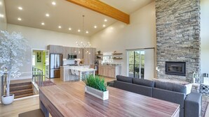 Amplia sala de estar con un gran comedor de madera, una chimenea de piedra y una cocina moderna con armarios de madera y horno empotrado.