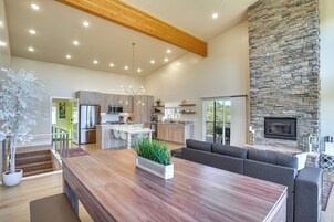 A spacious living area with a large wooden dining table, a stone fireplace, and a modern kitchen with wooden cabinets and a built-in oven.