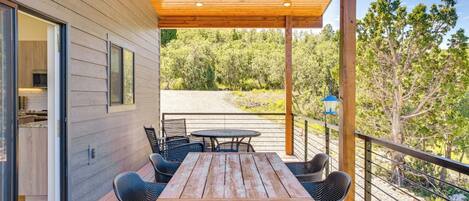 A wooden deck with a table and chairs, overlooking a forested area.