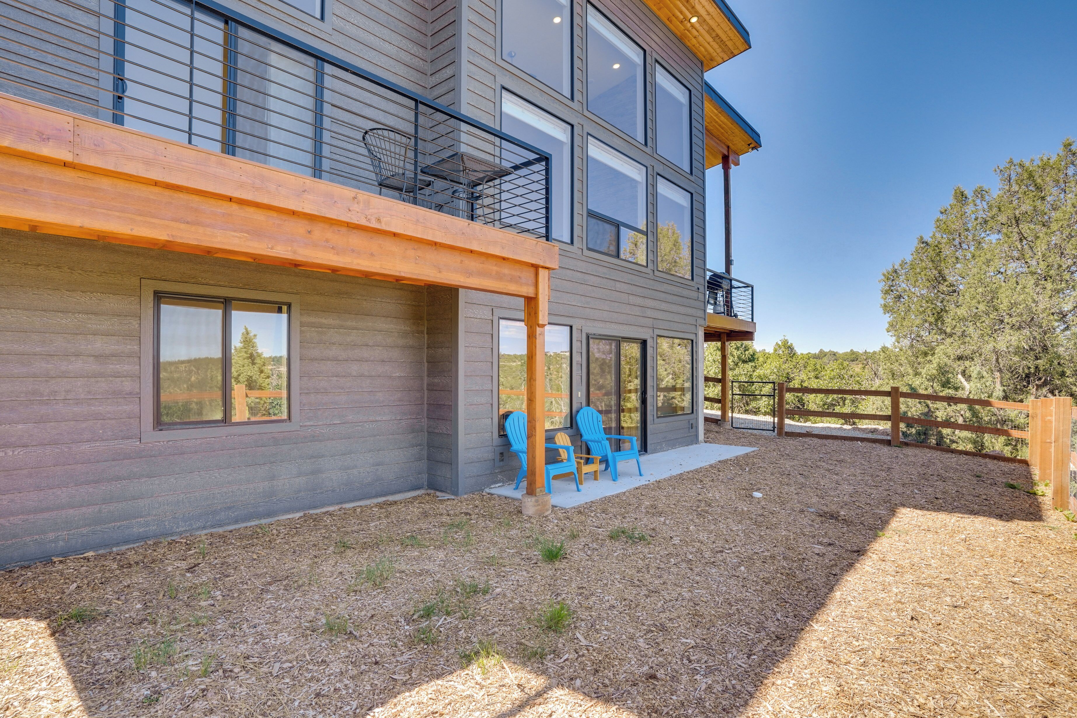 Une maison moderne à plusieurs étages, dotée d’un balcon, d’un espace extérieur aménagé pour s’asseoir et d’une terrasse en bois.