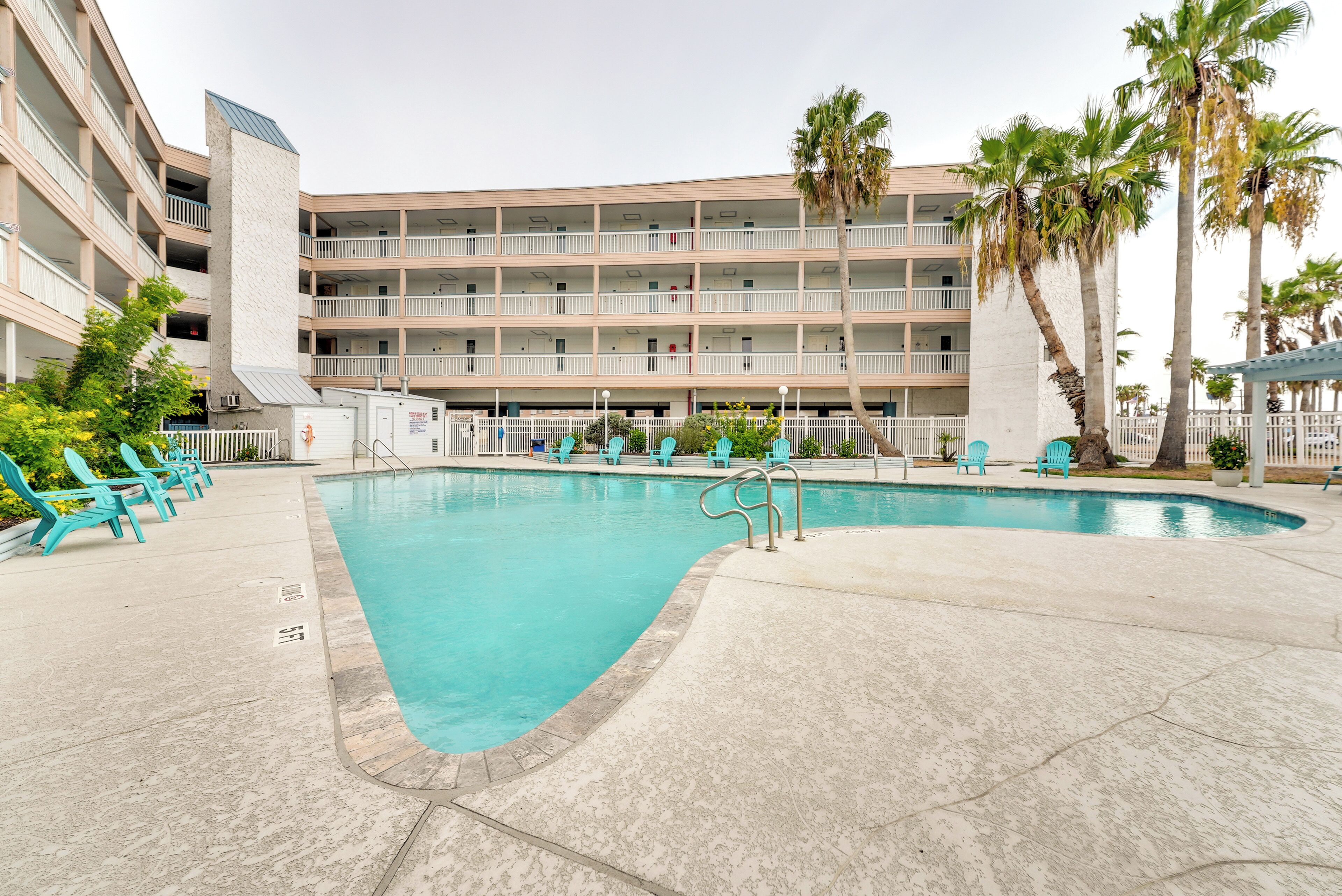 Un hotel con piscina, varios balcones y palmeras.