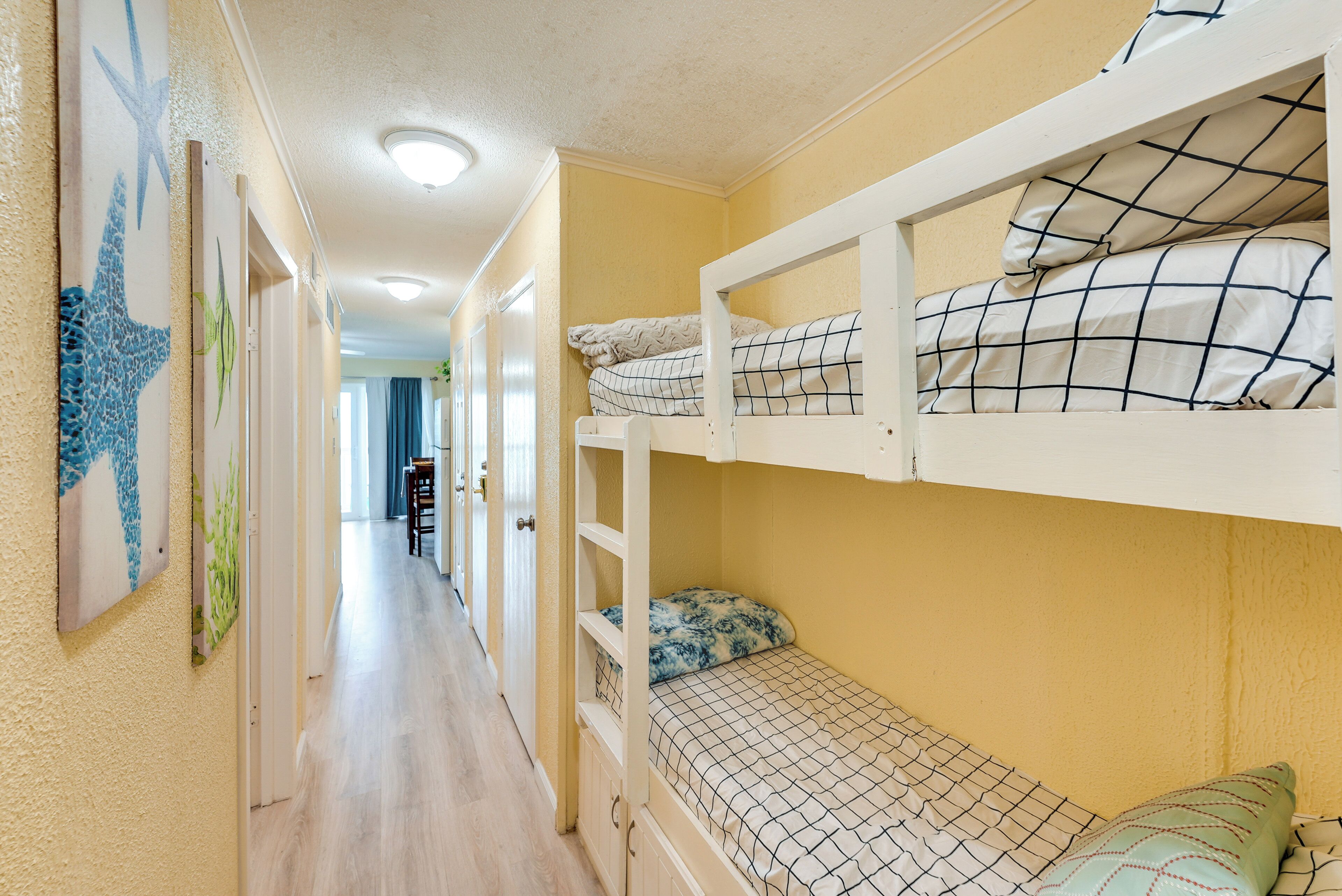 A narrow hallway with bunk beds on one side and a door leading to another room.
