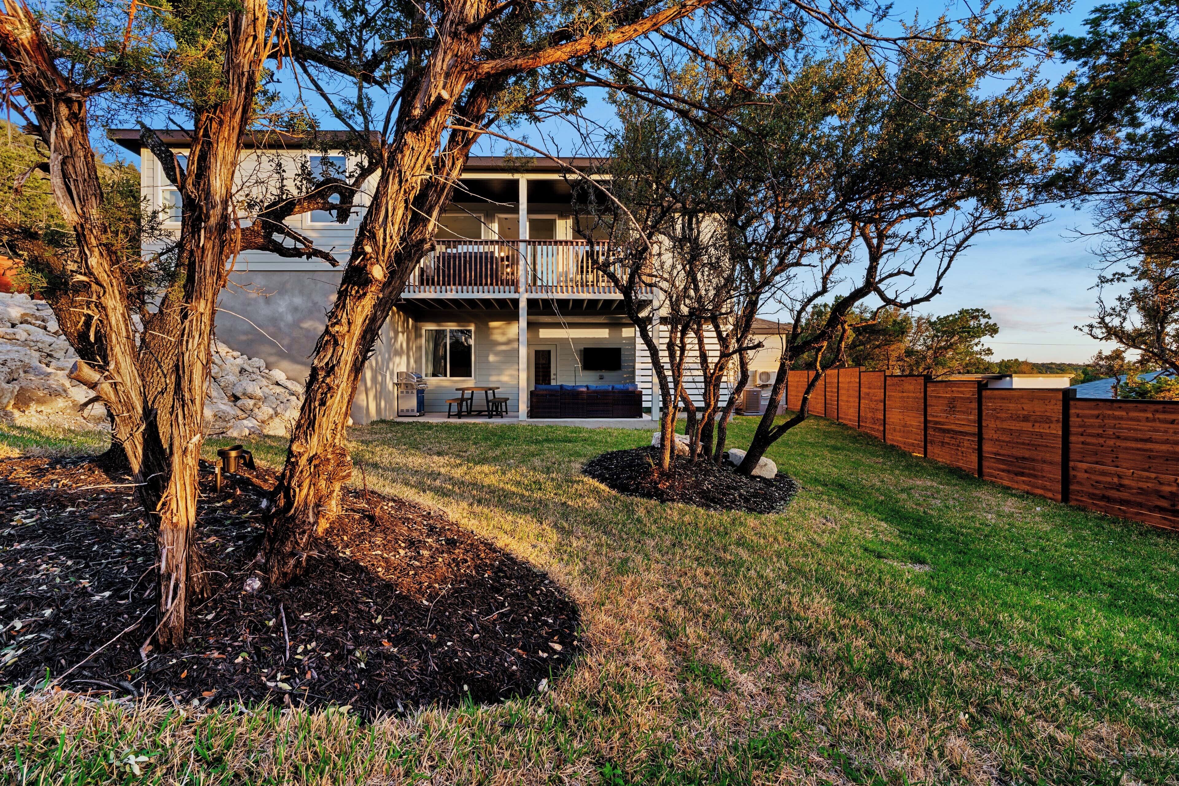 A two-story house with a balcony, surrounded by trees and a wooden fence.