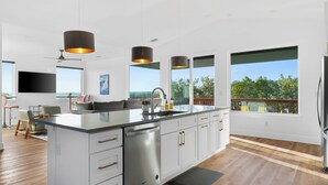 A modern kitchen with a large island, white cabinetry, stainless steel appliances, and pendant lighting. - Lago Vista Home w/ Game Room & Outdoor Tub! (Leander)