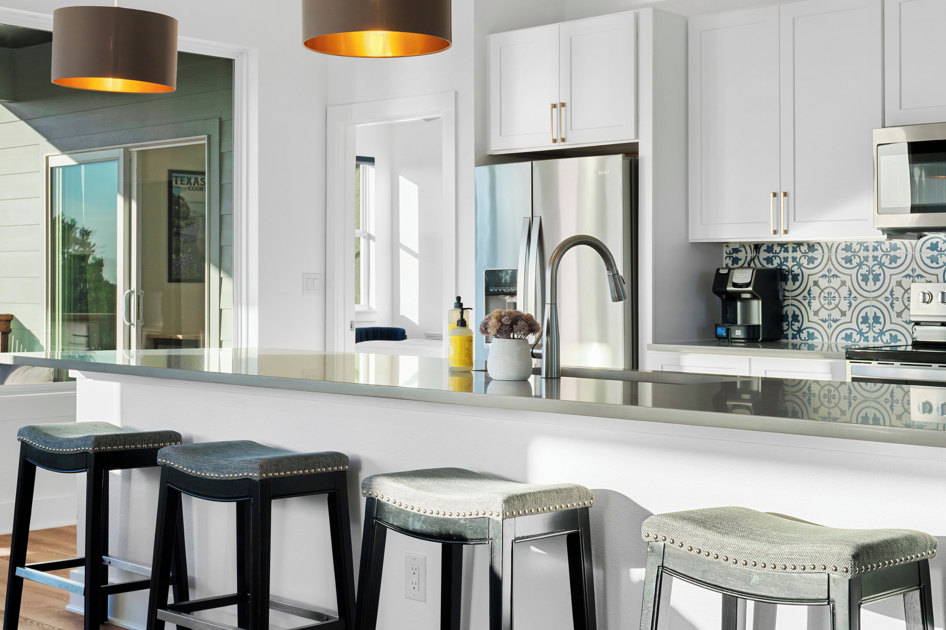 A modern kitchen with white cabinets, stainless steel appliances, and a large island with bar stools.