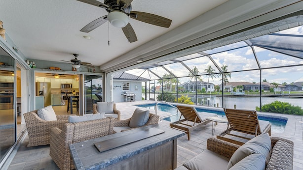 Um espaço amplo e coberto com piscina, assentos confortáveis e um bar.