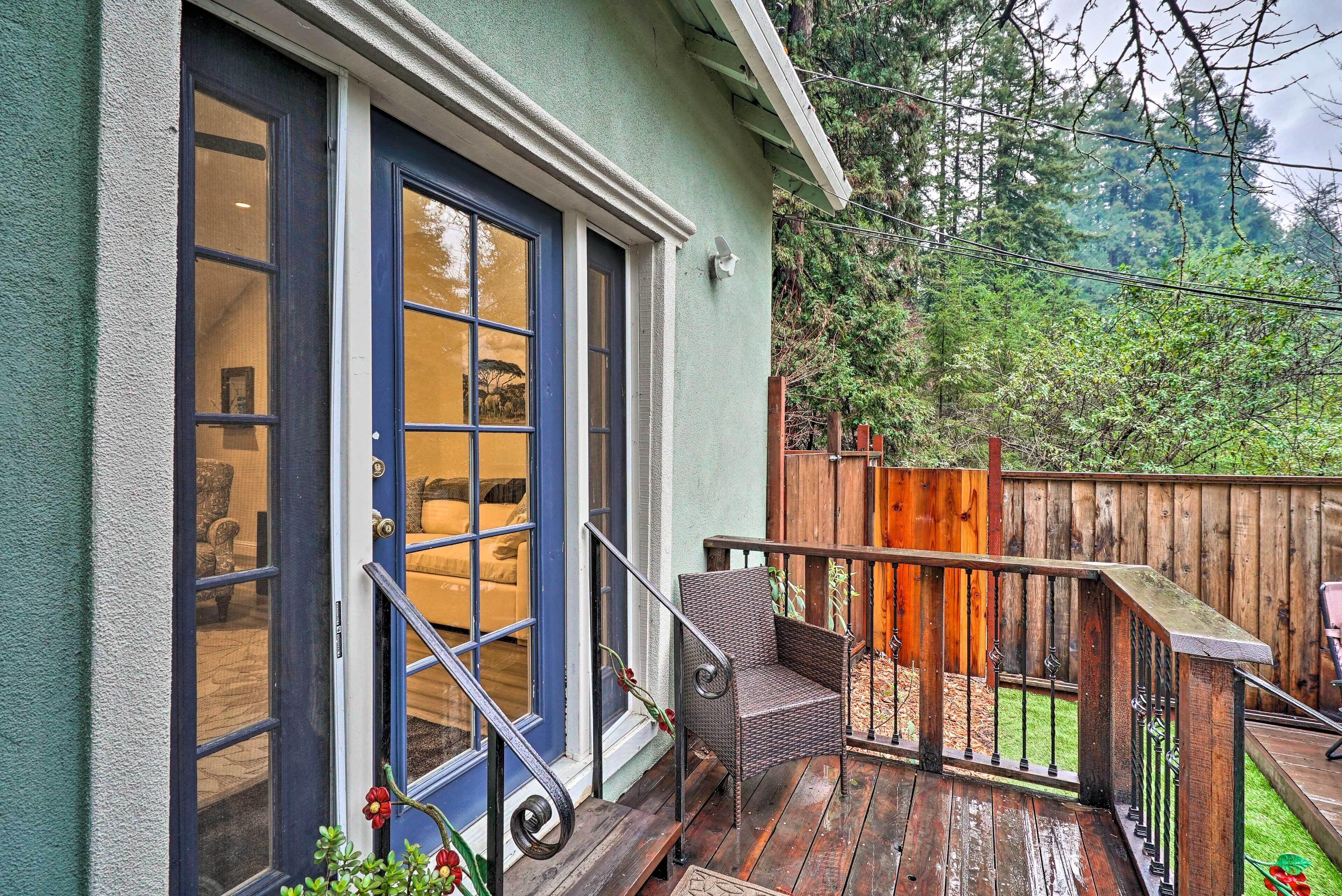Une terrasse en bois avec une chaise, une clôture en bois et une maison aux fenêtres à cadre bleu.