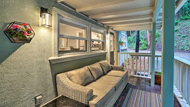 A covered porch with a wicker sofa, a striped rug, and a hexagonal planter with flowers. - California Cottage < 4 Mi to Redwood Hiking Trails (Ben Lomond)