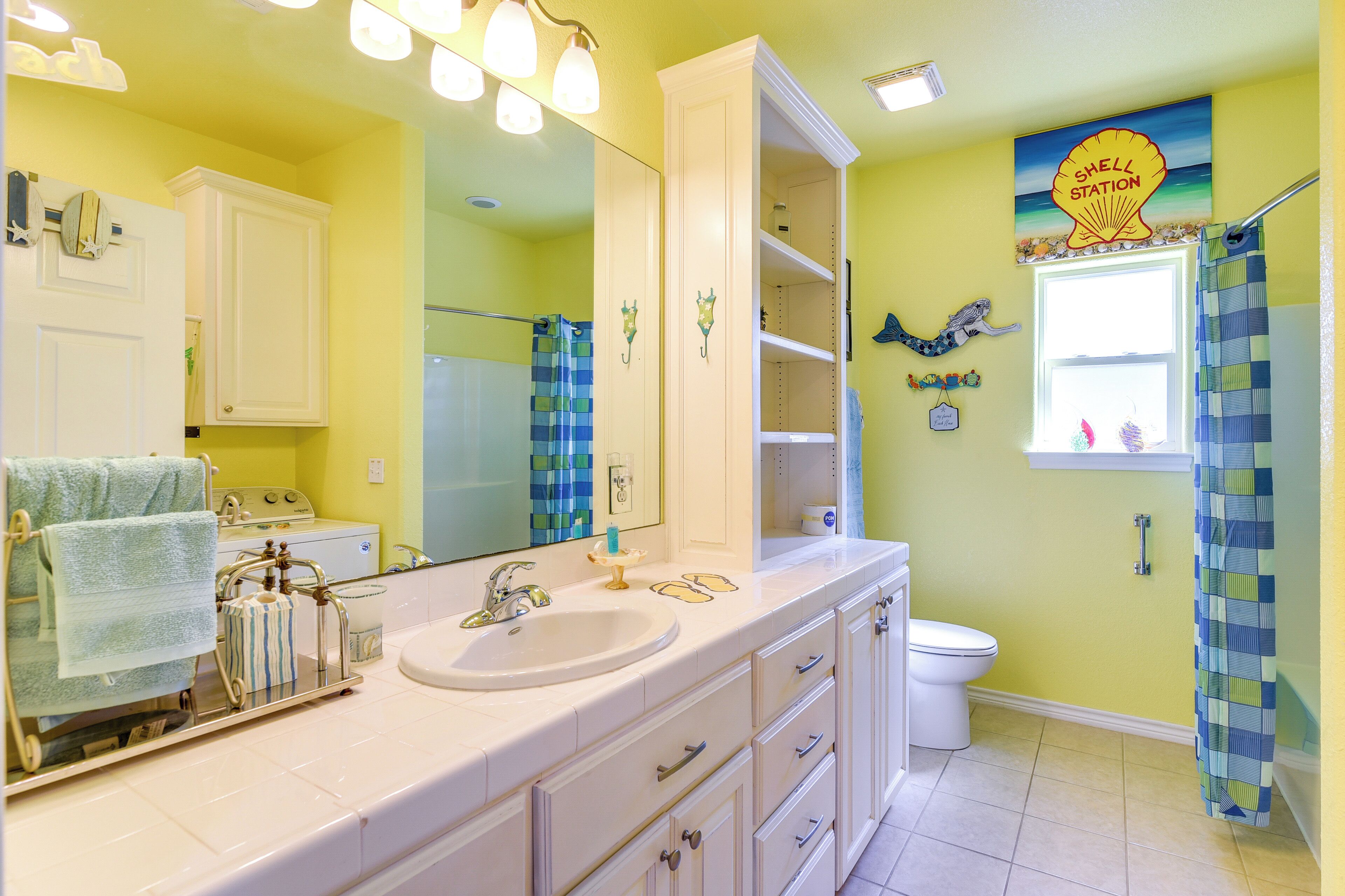 A bathroom with a white sink, a mirror, a toilet, and a shower curtain.