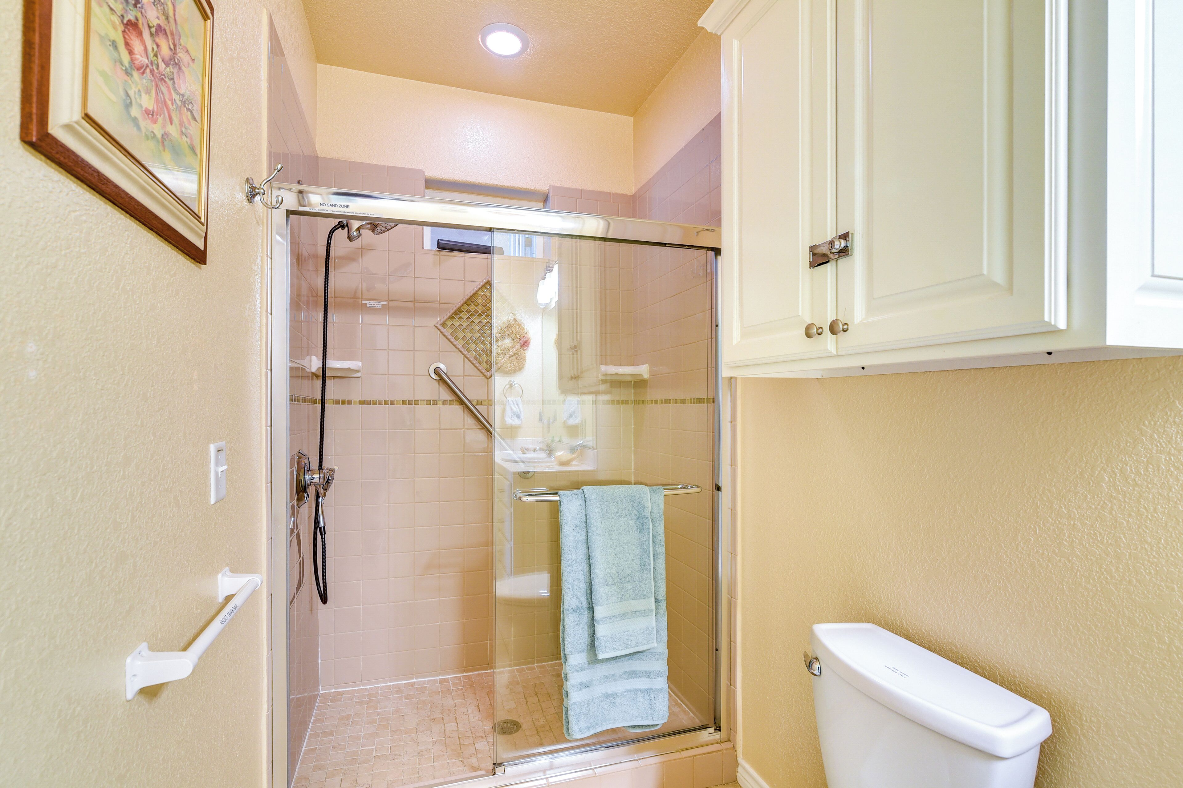 Une salle de bain avec une douche à parois de verre, des toilettes et un porte-serviettes.