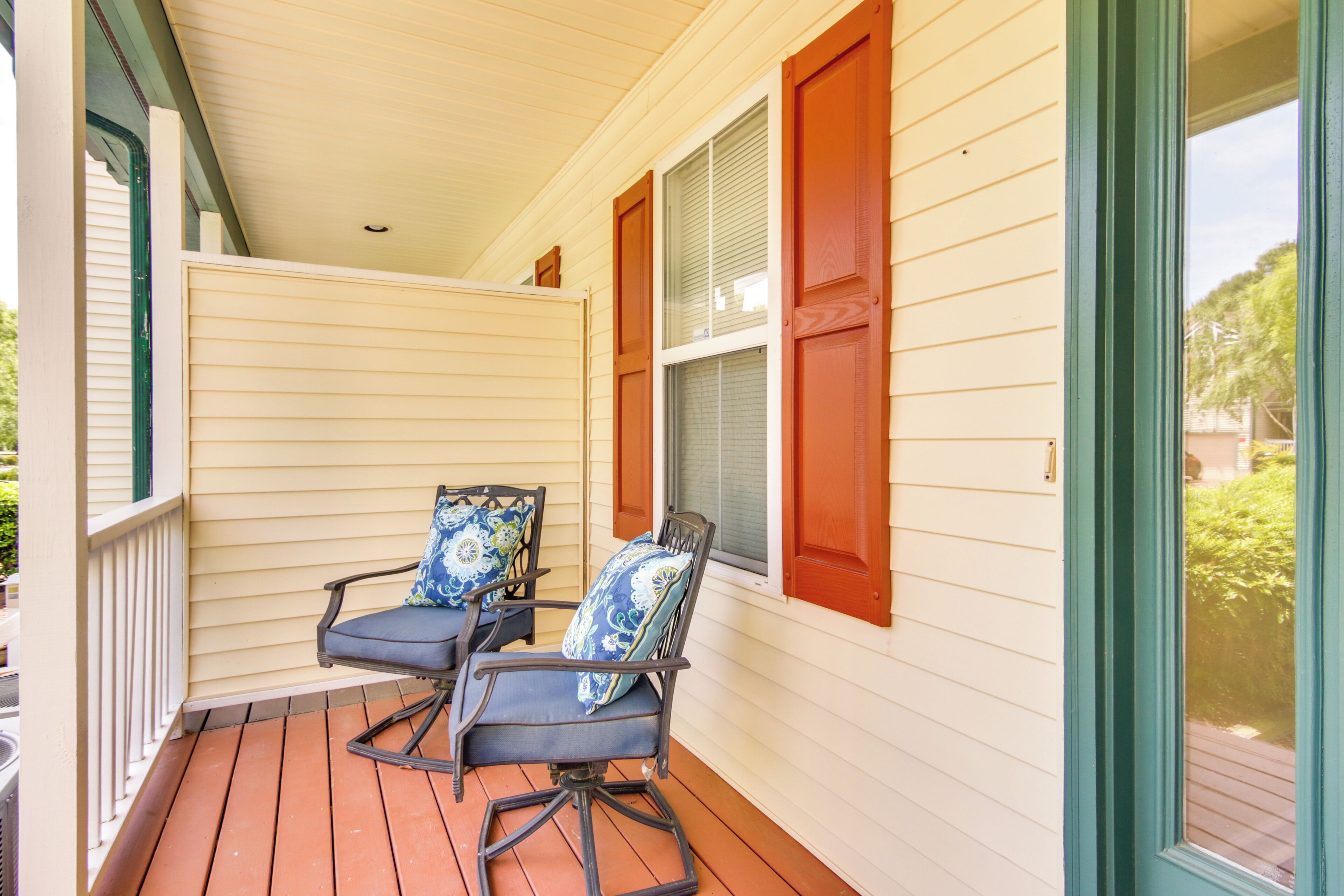 A porch with two rocking chairs and a window with red shutters.