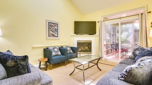 A living room with a sofa set, a glass coffee table, a fireplace, and a large sliding glass door leading to an outdoor area. - Poolside Fun & Beach Access in Ocean Pines! (Berlin)